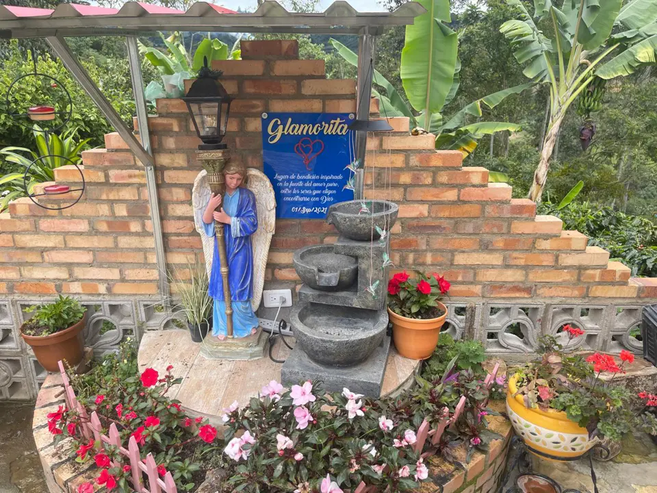 Flores, ladrillo y una pequeña fuente junto al letrero de Glamorita.