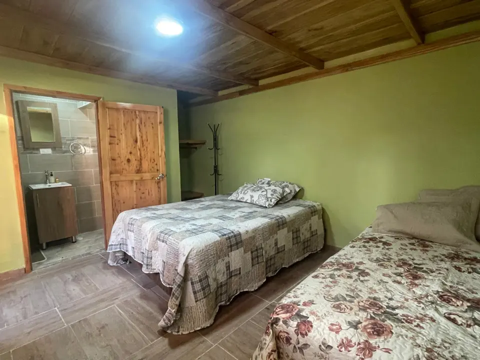La habitación iluminada, con sus camas y techo de madera.