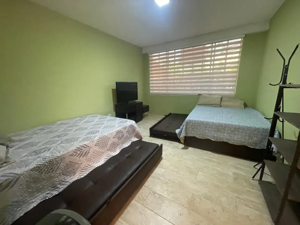 Una habitación de paredes verdes con dos camas.