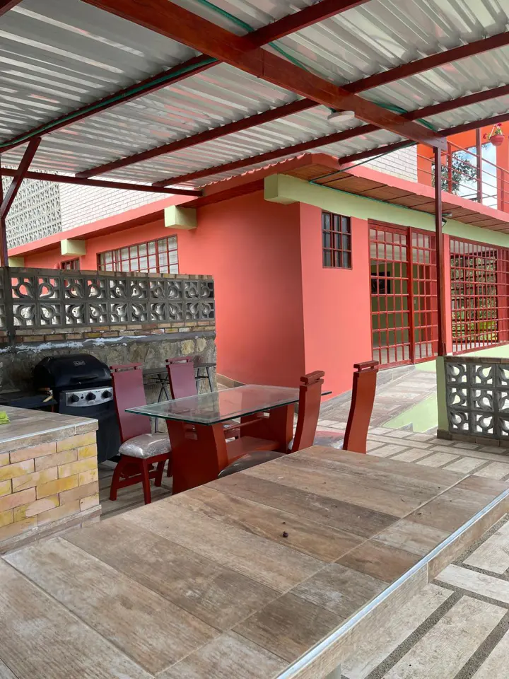 Mesas de madera y sillas en el comedor abierto de la finca.