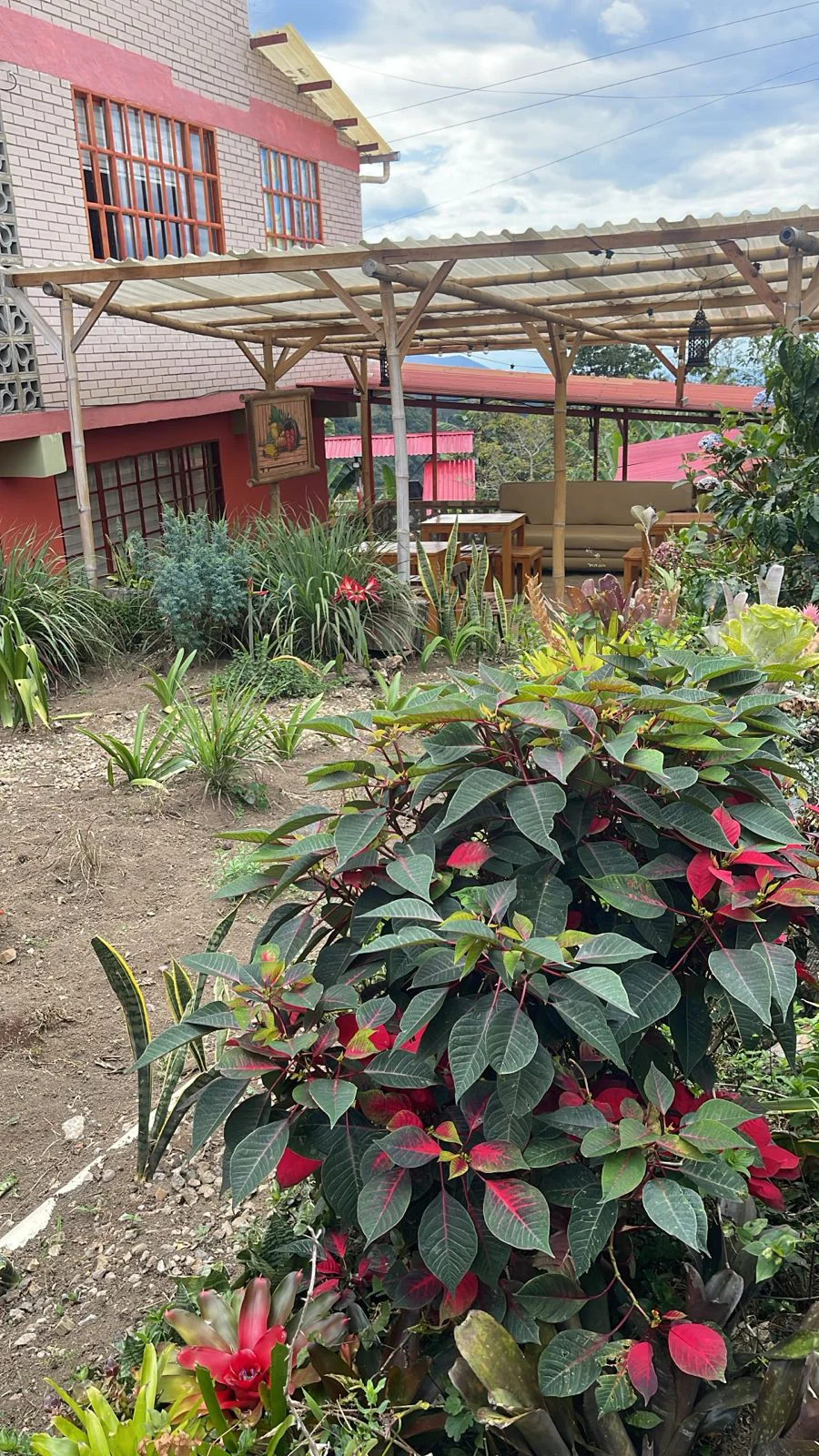 Jardín de Glamorita con flores, vegetación y una zona de descanso bajo una pérgola
